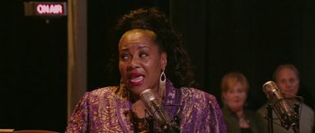 Movie still from “A Prairie Home Companion” (2006), directed by Robert Altman – An older woman with big hair is speaking into a microphone; Close Up shot, High angle