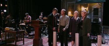 Movie still from “A Prairie Home Companion” (2006), directed by Robert Altman – A group of men and women standing next to each other; Wide shot, Over the shoulder angle
