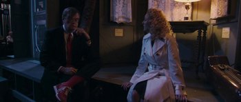 Movie still from “A Prairie Home Companion” (2006), directed by Robert Altman – A man and a woman sitting on a bench in front of a window; Medium shot, Over the shoulder angle