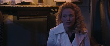 Movie still from “A Prairie Home Companion” (2006), directed by Robert Altman – A woman with curly blonde hair wearing a white jacket; Medium shot, Over the shoulder angle