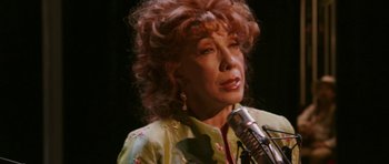 Movie still from “A Prairie Home Companion” (2006), directed by Robert Altman – An older woman is speaking into a microphone; Close Up shot, Over the shoulder angle