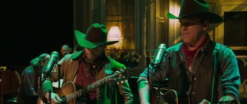 Movie still from “A Prairie Home Companion” (2006), directed by Robert Altman – A man in a cowboy hat playing a guitar; Medium shot, Low angle