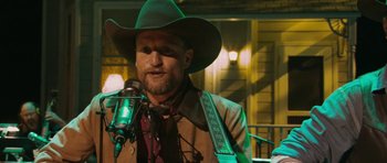 Movie still from “A Prairie Home Companion” (2006), directed by Robert Altman – A man in a green cowboy hat is speaking into a microphone; Close Up shot, Over the shoulder angle