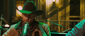 Movie still from “A Prairie Home Companion” (2006), directed by Robert Altman – A man in a cowboy hat is singing into a microphone; Close Up shot, Low angle