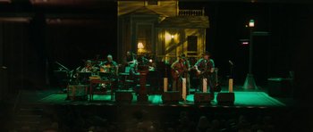 Movie still from “A Prairie Home Companion” (2006), directed by Robert Altman – A group of people on a stage playing instruments; Extreme Wide shot, High angle