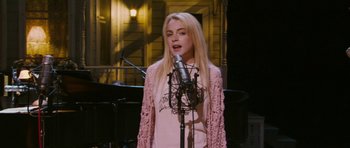 Movie still from “A Prairie Home Companion” (2006), directed by Robert Altman – A woman is singing into a microphone in front of a piano; Medium shot, High angle