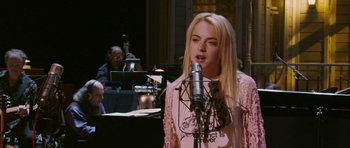 A woman is singing into a microphone in front of an orchestra