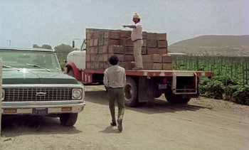 Movie still from “Alambrista!” (1977), directed by Robert M. Young – Two men standing on the back of a flatbed truck; Wide shot, Low angle