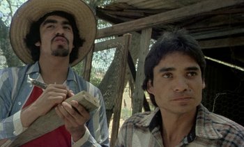 Movie still from “Alambrista!” (1977), directed by Robert M. Young – Two men are standing in front of a wooden structure; Close Up shot, Low angle