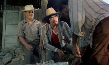 Movie still from “Alambrista!” (1977), directed by Robert M. Young – Two men sitting next to each other on the ground; Medium shot, Over the shoulder angle