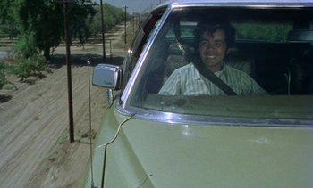Movie still from “Alambrista!” (1977), directed by Robert M. Young – A man sitting in the driver's seat of a green car; Medium shot, High angle