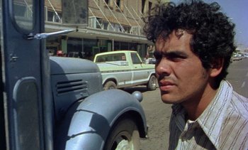 Movie still from “Alambrista!” (1977), directed by Robert M. Young – A man standing in front of a parking meter; Close Up shot, Low angle