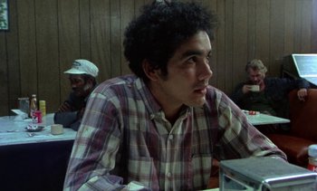 Movie still from “Alambrista!” (1977), directed by Robert M. Young – A man sitting at a table in front of other people; Close Up shot, Over the shoulder angle