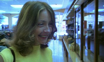 Movie still from “Alambrista!” (1977), directed by Robert M. Young – A woman smiling for the camera in a store; Close Up shot, Low angle