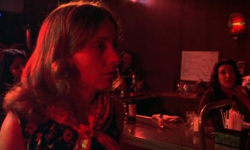 Movie still from “Alambrista!” (1977), directed by Robert M. Young – A woman sitting at a table in front of a glass of water; Close Up shot, Over the shoulder angle