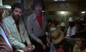 Movie still from “Alambrista!” (1977), directed by Robert M. Young – A group of people sitting in a room; Medium shot, Low angle
