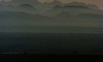 Movie still from “Alambrista!” (1977), directed by Robert M. Young – A train traveling on a train track near a mountain range; Extreme Wide shot, Low angle