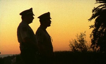 Movie still from “Alambrista!” (1977), directed by Robert M. Young – A couple of men standing next to each other on top of a field; Extreme Wide shot, Low angle