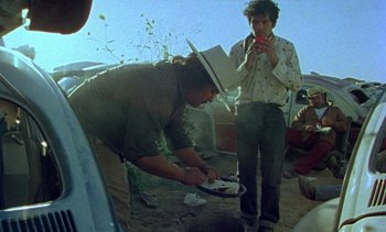 Movie still from “Alambrista!” (1977), directed by Robert M. Young – A man wearing a cowboy hat is holding a plate; Medium shot, Over the shoulder angle