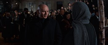Movie still from “Anastasia” (1956), directed by Anatole Litvak – A man in a black suit standing in front of a group of people; Medium shot, Over the shoulder angle