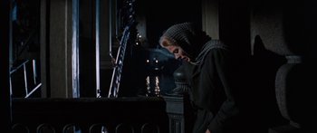 Movie still from “Anastasia” (1956), directed by Anatole Litvak – A woman standing next to a pillar in a dark room; Medium shot, Low angle