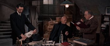 Movie still from “Anastasia” (1956), directed by Anatole Litvak – A group of people sitting at a table with books; Medium shot, High angle