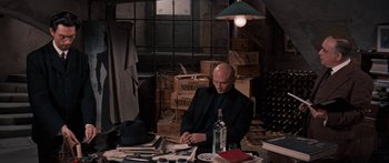 Movie still from “Anastasia” (1956), directed by Anatole Litvak – A man sitting at a table writing on a piece of paper; Wide shot, High angle