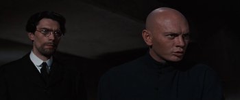Movie still from “Anastasia” (1956), directed by Anatole Litvak – A bald man in a black shirt is looking at the camera; Close Up shot, Low angle