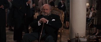 Movie still from “Anastasia” (1956), directed by Anatole Litvak – An old man sitting in a chair holding a cane; Medium shot, High angle