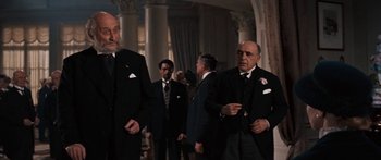 Movie still from “Anastasia” (1956), directed by Anatole Litvak – A group of men standing next to each other in suits; Medium shot, Over the shoulder angle