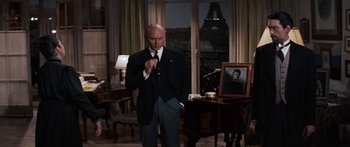 Movie still from “Anastasia” (1956), directed by Anatole Litvak – A man standing in a living room next to a table; Medium shot, Over the shoulder angle