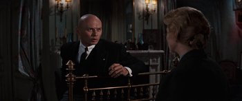 Movie still from “Anastasia” (1956), directed by Anatole Litvak – A man in a suit and tie next to a metal railing; Medium shot, Over the shoulder angle