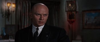 Movie still from “Anastasia” (1956), directed by Anatole Litvak – A man in a suit and tie with a bald head; Close Up shot, Low angle