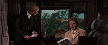 Movie still from “Anastasia” (1956), directed by Anatole Litvak – A man and a woman sitting at a table in front of a window; Medium shot, Over the shoulder angle