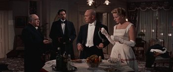 Movie still from “Anastasia” (1956), directed by Anatole Litvak – A group of people standing around a dinner table; Medium shot, Over the shoulder angle