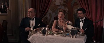 Movie still from “Anastasia” (1956), directed by Anatole Litvak – A woman sitting at a table with a man in a suit; Medium shot, High angle