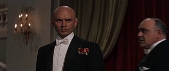 Movie still from “Anastasia” (1956), directed by Anatole Litvak – A bald man in a black suit with a medal around his neck; Close Up shot, Low angle