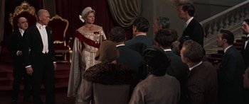 Movie still from “Anastasia” (1956), directed by Anatole Litvak – A group of people sitting in front of a woman in a white dress; Medium shot, Over the shoulder angle