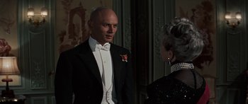 Movie still from “Anastasia” (1956), directed by Anatole Litvak – A man in a tuxedo standing next to a woman in a black dress; Medium shot, Over the shoulder angle