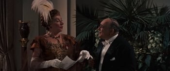 Movie still from “Anastasia” (1956), directed by Anatole Litvak – An older man and woman in formal wear holding papers; Medium shot, Over the shoulder angle