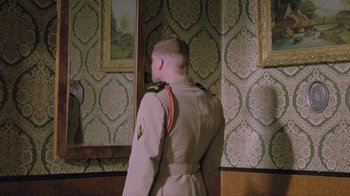 Movie still from “Antonia's Line” (1995), directed by Marleen Gorris – A man in a uniform looking in a mirror; Medium shot, Over the shoulder angle