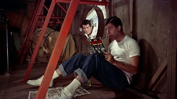 Movie still from “Artists and Models” (1955), directed by Frank Tashlin – A man sitting on the ground reading a magazine; Medium shot, Low angle