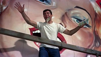 Movie still from “Artists and Models” (1955), directed by Frank Tashlin – A man standing in front of a painting of a woman's mouth; Medium shot, Low angle