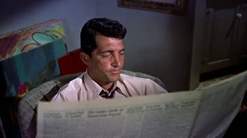 Movie still from “Artists and Models” (1955), directed by Frank Tashlin – A man sitting in a chair looking at a newspaper; Medium shot, Over the shoulder angle