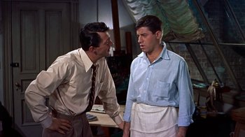 Movie still from “Artists and Models” (1955), directed by Frank Tashlin – Two men talking to each other in front of a table; Medium shot, Over the shoulder angle