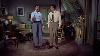 Movie still from “Artists and Models” (1955), directed by Frank Tashlin – Two men standing next to each other in a living room; Wide shot, Low angle