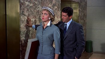 Movie still from “Artists and Models” (1955), directed by Frank Tashlin – A man and a woman standing next to each other in front of a building; Medium shot, Low angle