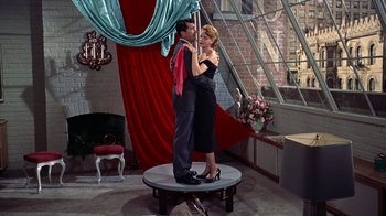 Movie still from “Artists and Models” (1955), directed by Frank Tashlin – A man and a woman standing on a pole in front of a window; Wide shot, High angle
