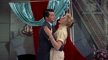 Movie still from “Artists and Models” (1955), directed by Frank Tashlin – A man and a woman dancing in front of a red curtain; Medium shot, Low angle