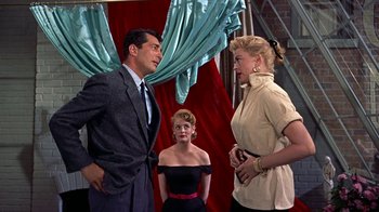 Movie still from “Artists and Models” (1955), directed by Frank Tashlin – Two women and a man standing in front of a red curtain; Medium shot, Over the shoulder angle